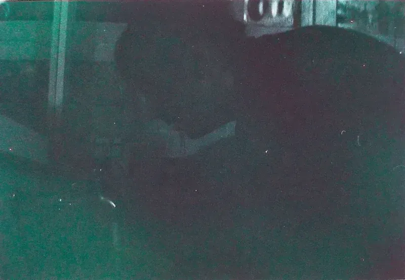 A dark, grainy close-up portrait with green and violet tones