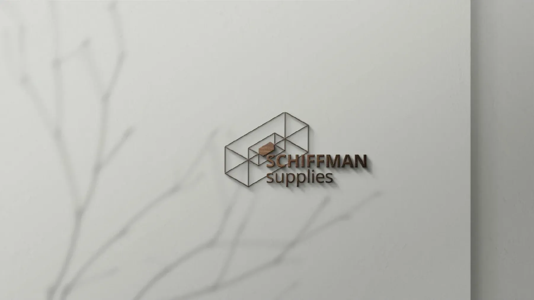 Three-dimensional metal Schiffman logo mounted on a light wall, casting a geometric shadow.